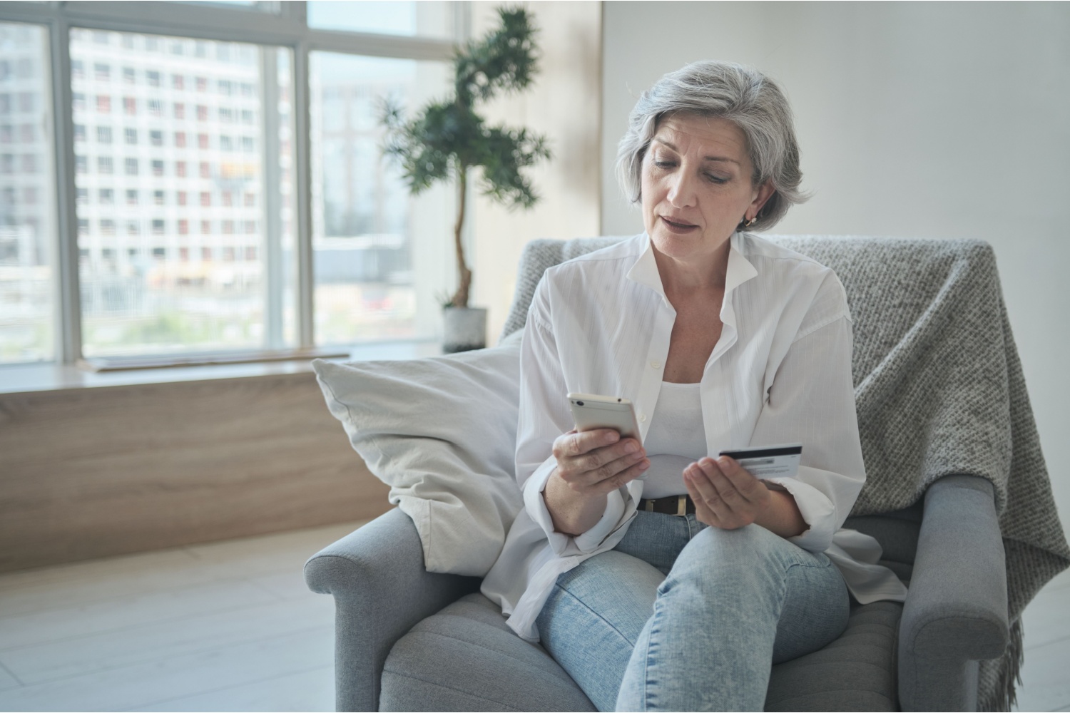 Retired lady sitting in comfortable surroundings shopping on phone.