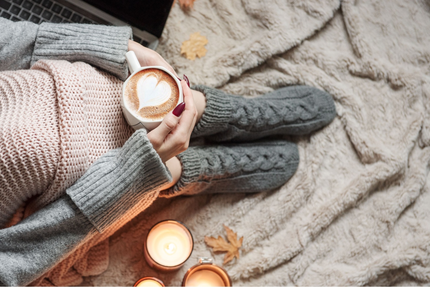 Woman wearing cosy socks, wrapped in blanket, holding a cup of coffee