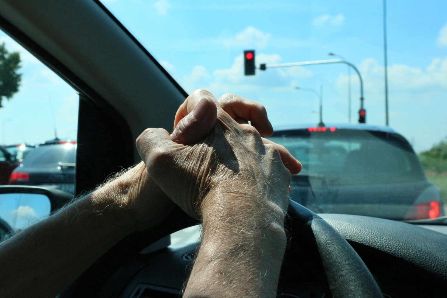 Man stuck in a car at red light in traffic jam, not going anywhere.