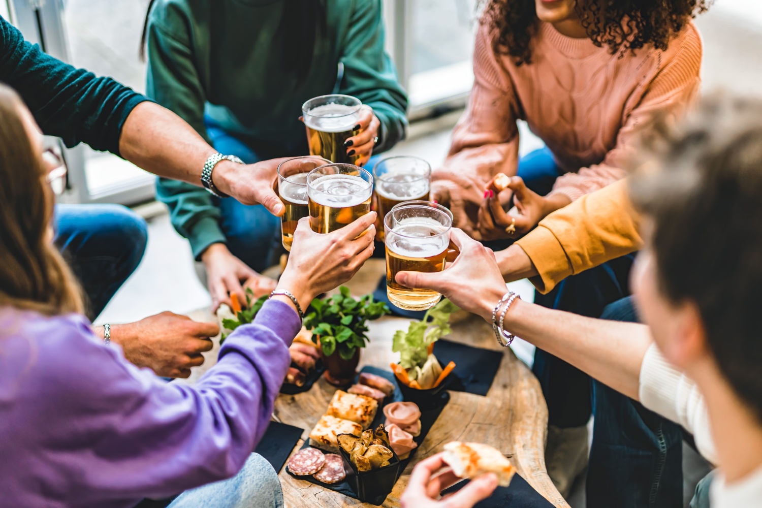 Family round table of food and toasting with beer glasses.