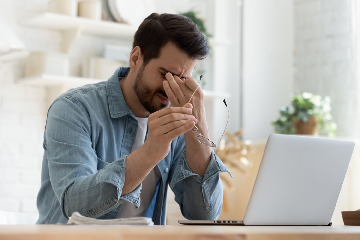 A man at his computer looking stressed.