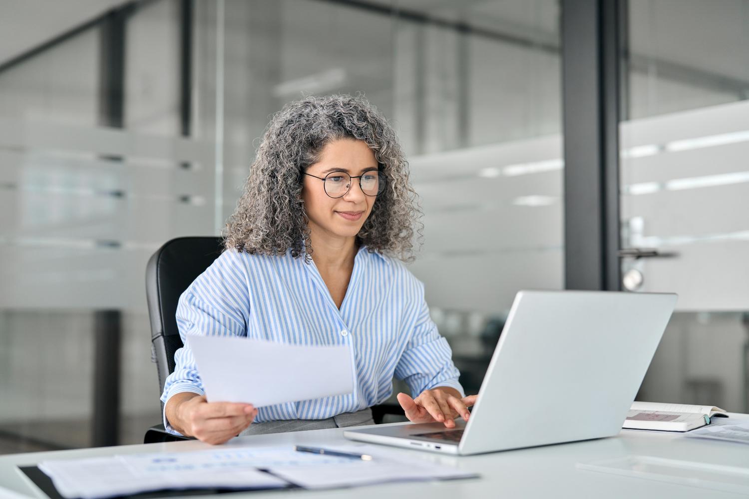 Middle-aged woman busy working at laptop.