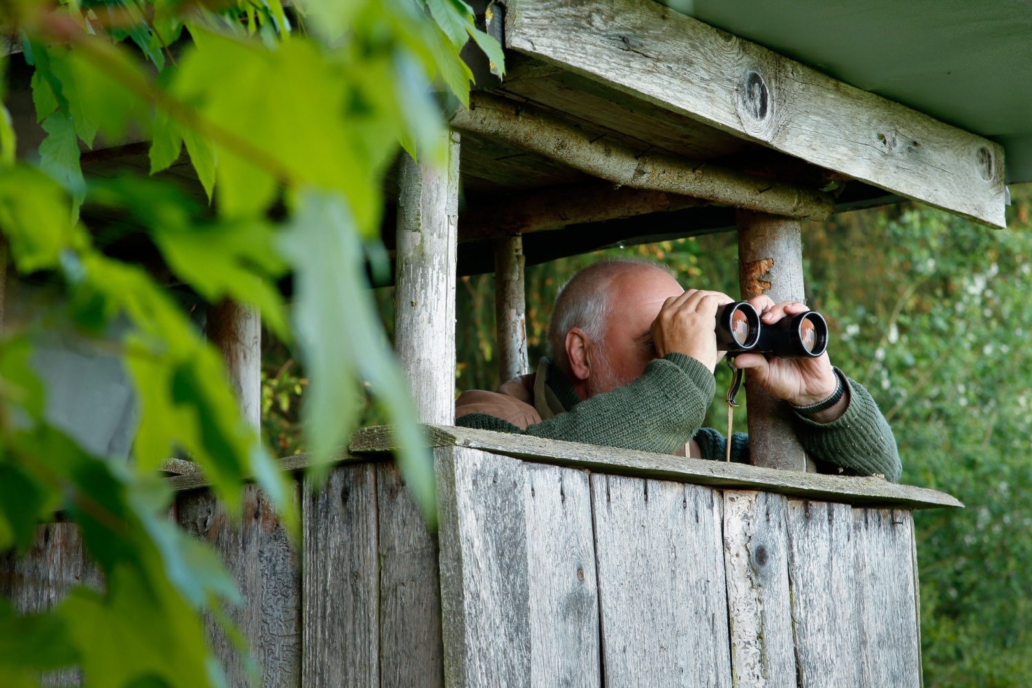 A man peering out from a pulpit with binoculars.