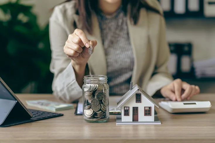 A woman putting a coin into a savings pot.