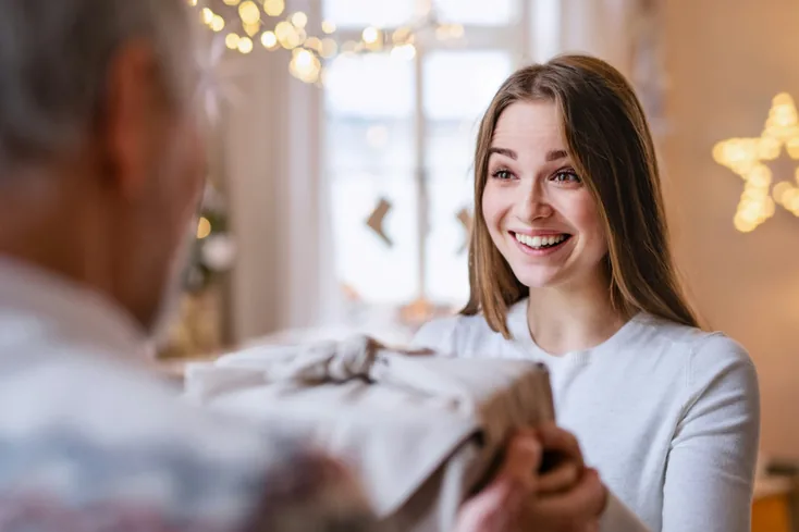 Smiling young woman receives a gift from an older relative.