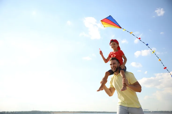 A father and child flying a kite.