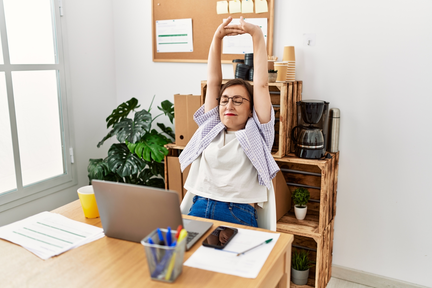 A woman stretching at her desk.